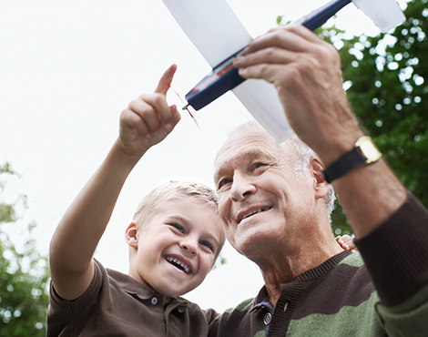 Older person flying a toy airplane with his grandson